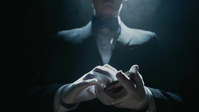 Close-up of a Suited Magician's Hands Performing Sleight of Hand Card Tricks. Cards fly and turn over in the air. Slow Motion. Background is Black.