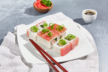 Maki sushi  with tuna and green onion on wooden board in aesthetic composition. Simple sushi roll with tuna on concrete table. Fresh sushi roll in minimal style.