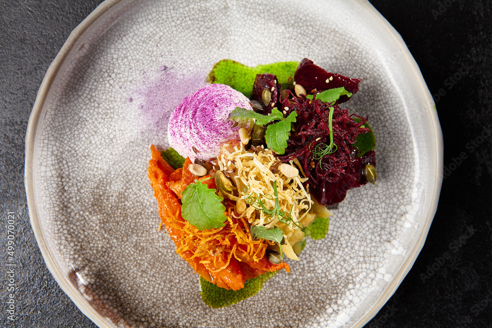 Wall mural baked root vegetables in handmade ceramic dishware. vegan food - caramelized carrot, beetroot and ce