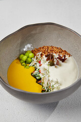 Pumpkin soup with crab in handmade ceramic bowl. Innovative recipes - cream soup with crab and cheese espuma on white concrete background. Modern food in dishware.