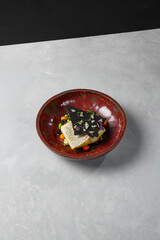 Cooked white fish steak on vegetables balls. Fish fillet with vegetables garnish in handmade ceramic dishware on gray concrete table. Minimalistic modern food composition.