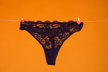 Lace panties. The sexy panty isolated on the yellow background. Black silk lacy panty, woman underwear, sexy lingerie. Thong bikini panties underwear lingerie. - obrazy, fototapety, plakaty