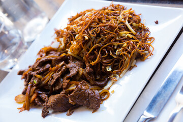 Asian cuisine. Delicious beef with onions and noodles served on white plate