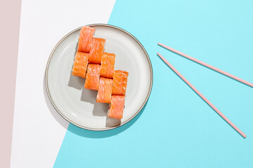 Salmon maki roll with red caviar on modern coloured background. Sushi roll with Philadelphia cheese, caviar inside, salmon outside. Moscow maki sushi in minimal style. Japanese menu concept. © Ryzhkov