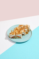 Maki roll with tuna shavings on modern coloured background. Sushi roll with salmon, cheese, cucumber inside, tuna shaving outside. Bonito maki sushi in minimal style. Japanese menu concept.