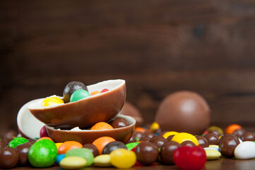 Happy Easter greeting card. composition with delicious sweets, chocolate eggs on wooden background, space for text.