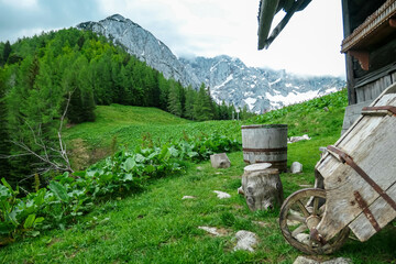 Mountain hut with panoramic on green alpine meadows and rocky sharp cloud covered mountain peaks of...