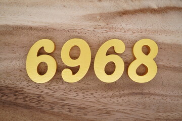 Golden Arabic numerals on a real brown and white wooden floor number 6968