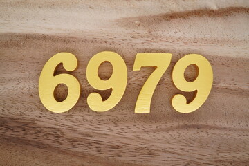 Golden Arabic numerals on a real brown and white wooden floor number 6979