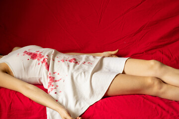 A murdered and tortured Ukrainian woman in a white dress and bloodstains lies on a bed at home, a protest action of Ukrainian women protecting women from Russian
