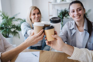 Business women celebrate work success with male colleagues by making a clink of a coffee cup