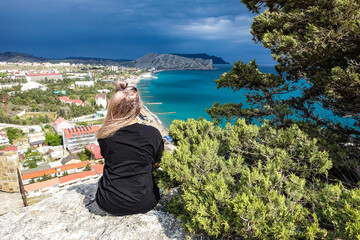 Fototapeta na wymiar A girl on the background of a view from the Genoese fortress to the Sudak Bay. Sudak May 2021.