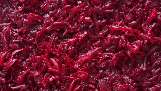 Background and texture of raw fresh juicy grated red beetroot vegetable, close up, top view, rotates