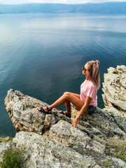 A girl on the background of a view of Lake Baikal at the Shamanka rock. Irkutsk region. Russia.