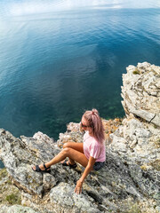 Fototapeta na wymiar A girl on the background of a view of Lake Baikal at the Shamanka rock. Irkutsk region. Russia.