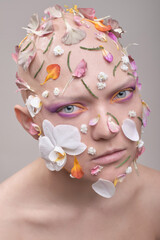 A beautiful woman without hair with flowers on her head, a conceptual photo with an unusual model