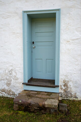 Blue colonial wooden door in whitewashed stone cottage