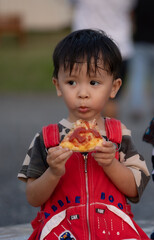 Portrait of Asia boy eating pizza in the farm
