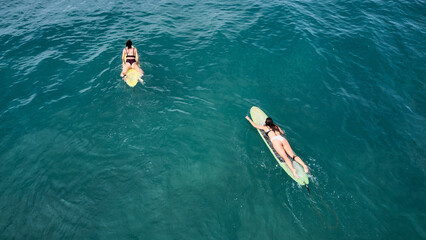 Aerial view of the ocean and surfer girls.