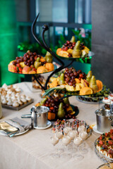 Wedding. Candy bar. On the buffet table there are glasses with drinks, fruits and different sweets.