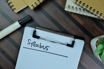 Syllabus write on a paperwork isolated on Wooden Table.