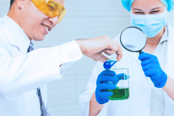 Scientist team in uniform holding beaker and test tube have chemical liquid for testing chemical reaction.