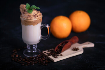 Korean dalgona coffee in composition with coffee beans and oranges