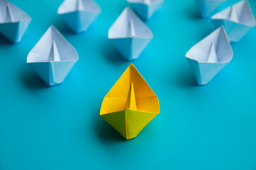 Leadership Concept - Yellow color paper ship origami leading the rest of the white paper ship on...
