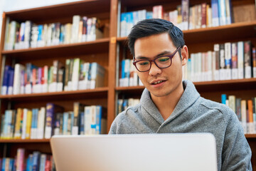 He only strives for success through hard work. Shot of a focused young man busy working on his laptop and studying while being seated inside of a library.