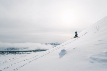 Snowbike rider riding on steep snowy slope. Modify motorcycle with ski and special snowmobile-style track instead of wheels