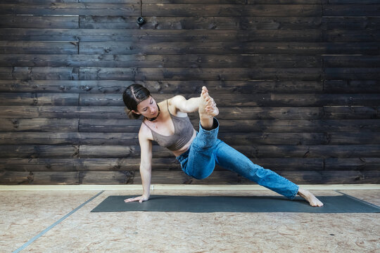 Young woman wearing jeans doing yoga at home
