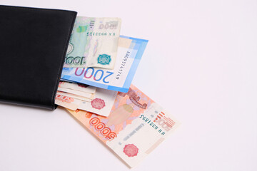 Russian rubles in denominations of one, two and five thousand rubles in a purse on a white background.