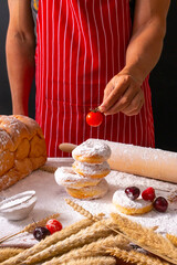 Hand of a man making homemade bread and donut on wooden table in his house.