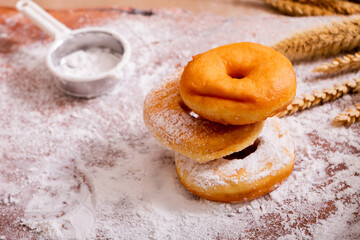 Donuts with white flour on wooden table.