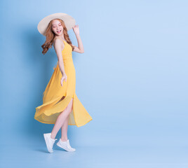 Full length image of young Asian woman wearing yellow dress on blue background