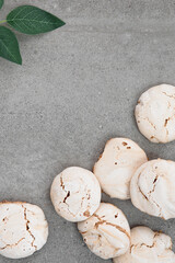 Meringue on the kitchen table. Meringue bottom right. Meringue on a gray background. Place for text. Green branch on the table.
