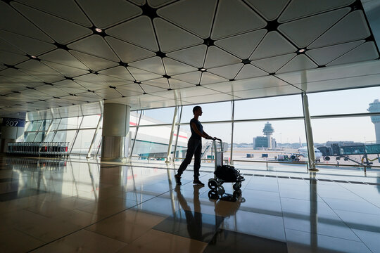 Traveling concept. Silhouette of young woman with baggage in international airport terminal.