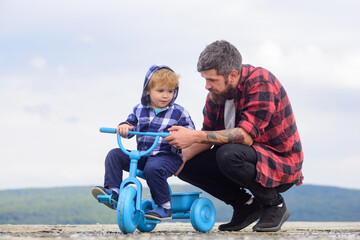 Father and son cycling with kids bike outdoor. cute Little boy learn to ride a bike with his daddy. Dad teaching son to ride bicycle.