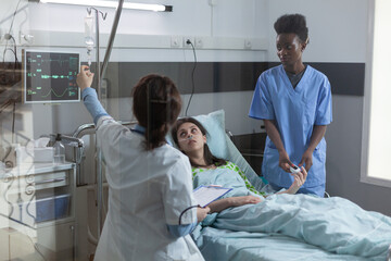 Doctor setting up central line catether with iv drip medication to patient while nurse is putting...