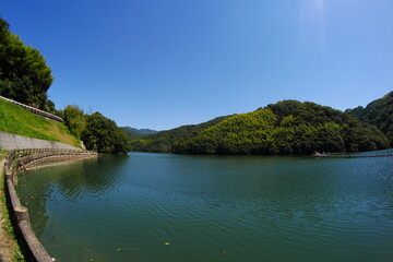 青空の下の山の中のダム湖
