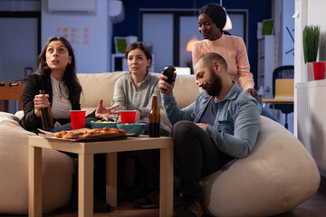 Sad man losing video games play online with controller on tv console at office party, attending drinks celebration after work. Colleagues doing leisure activity with beer, pizza, snacks and game.