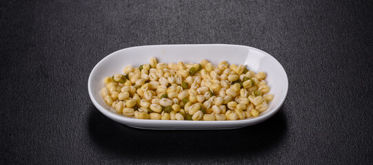 Organics fresh Baby Green Bean Sprouts in white ceramic bowl on a dark concrete background