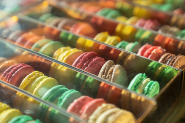 Assortment of colorful french macaroons on cafe showcase for sale . Variety of macaron flavours. Sweet almond cakes in store. Cookies in the shop on storefront