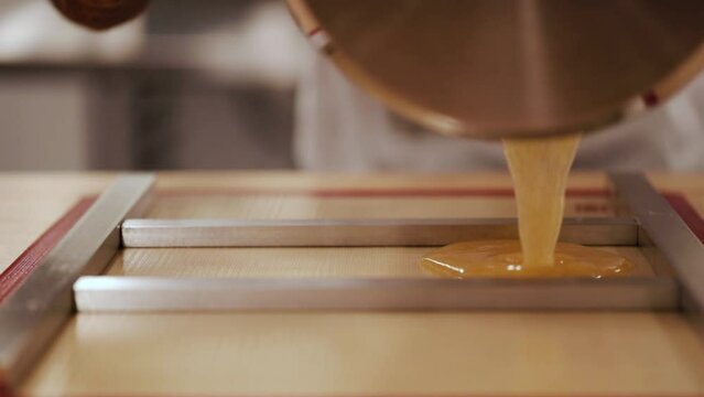 chef pouring hard candy mix into tray.