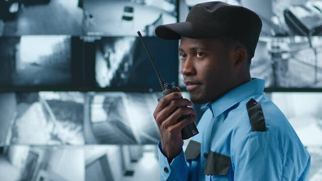 Side view of African-American security guard talk on radio in control room