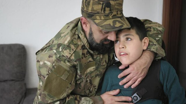 Military soldier kissing his son with disability at home