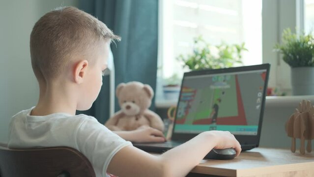 Little boy playing online game or video game using laptop.
