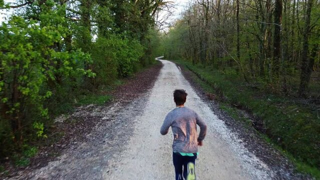 Personne courant sur un chemin &agrave; l'ombre des arbres. Homme qui court sur un chemin forestier.