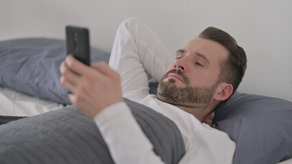 Man using Smartphone while Laying in Bed