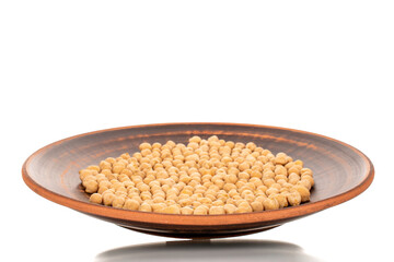 Several uncooked hummus grains on a clay plate, macro, isolated on white.